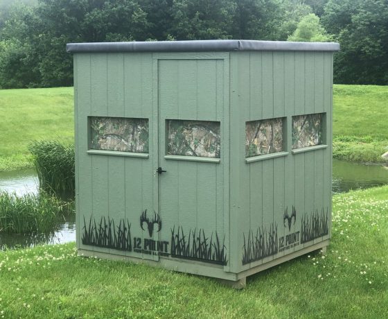 a green square hunting blind box for sale next to a small pond